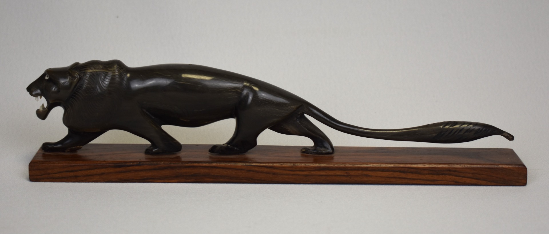 Leu Art Deco sculptat în corn de animal – vedere laterală, statuetă decorativă pe bază din lemn